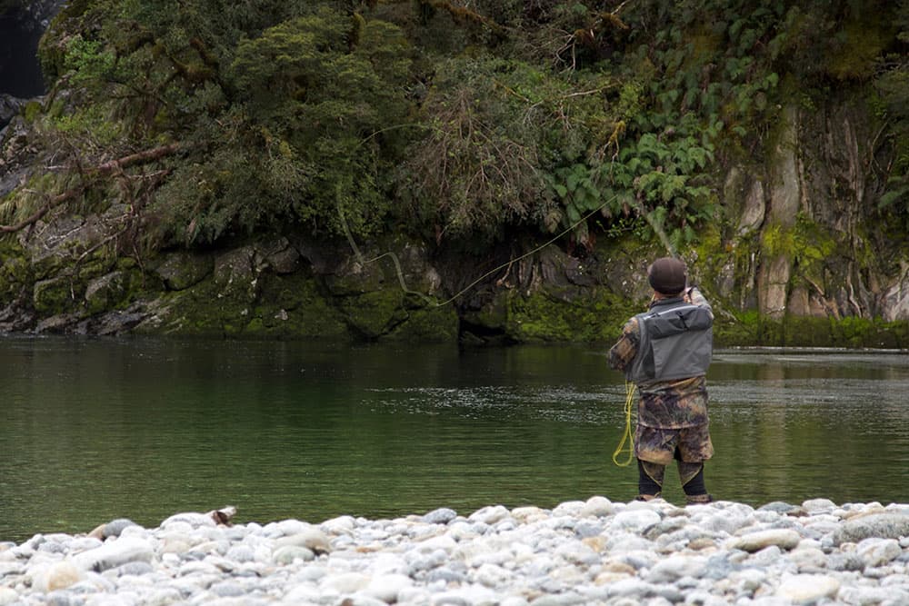 An angler fly fishing from a riverbank